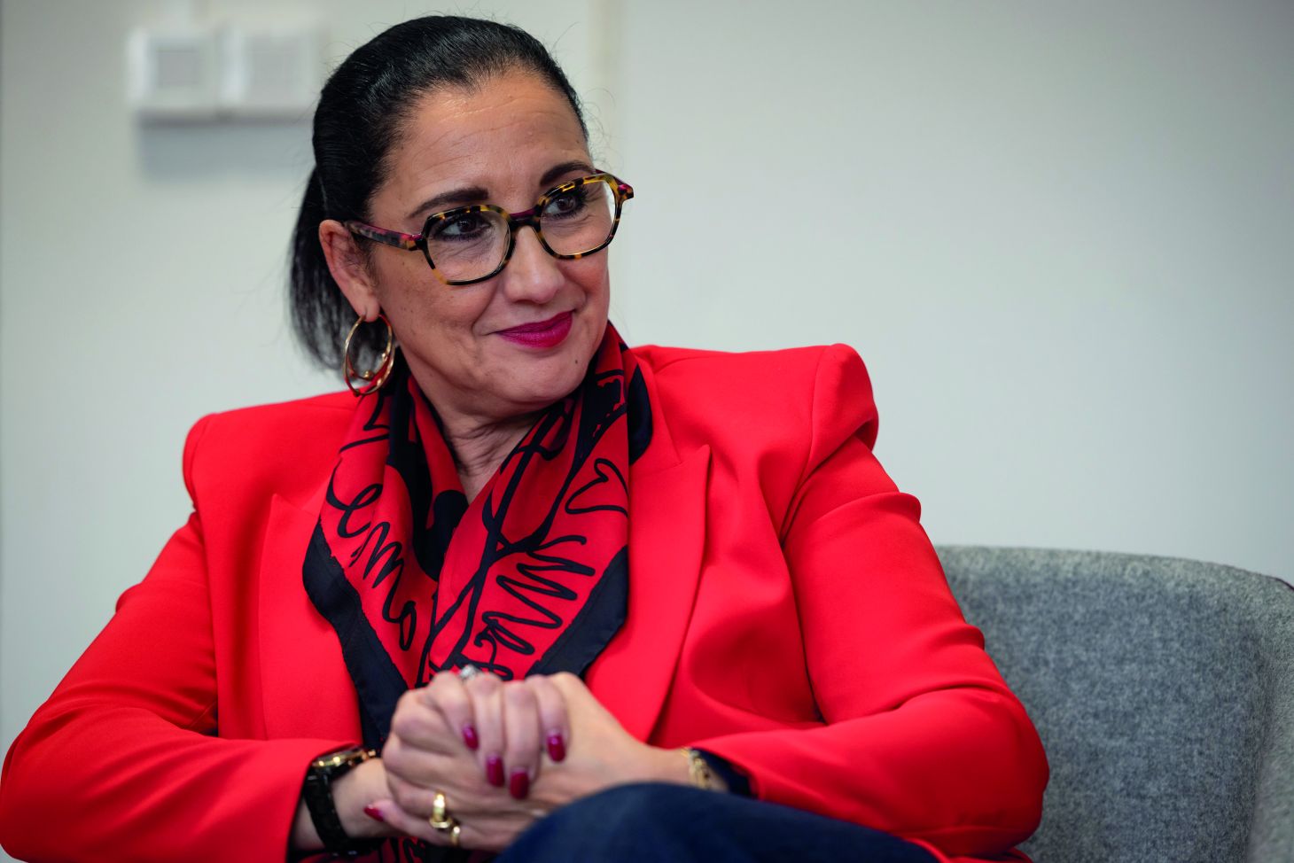 Photo : Fadila Khattabi, ministre déléguée chargée des personnes handicapées, assise, les mains croisées et tout sourire.